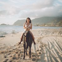 Photograph from lifestyle photography session picturing a girl on a horse on a beach in Hawaii.