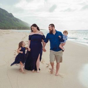 Family of 4 walking the beach on Oahu's North Shore during moody sunset session.