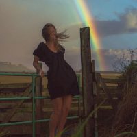 Photograph of model posing for lifestyle session. Vibrant sunset colors with rainbow