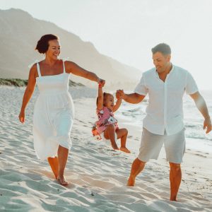 Oahu Family Photographer capturing beautiful moment between mother, father and daughter during sunset family portrait session at remote beach on Oahu's North Shore, Hawaii.